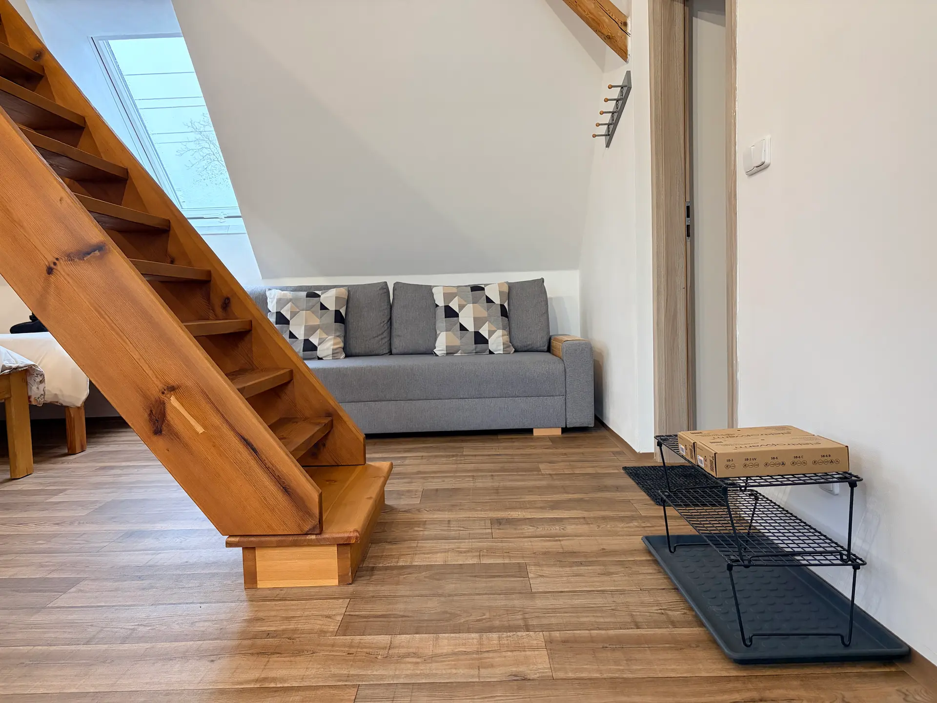 Obývací část apartmánu 2 s pohovkou a schodištěm do podkroví